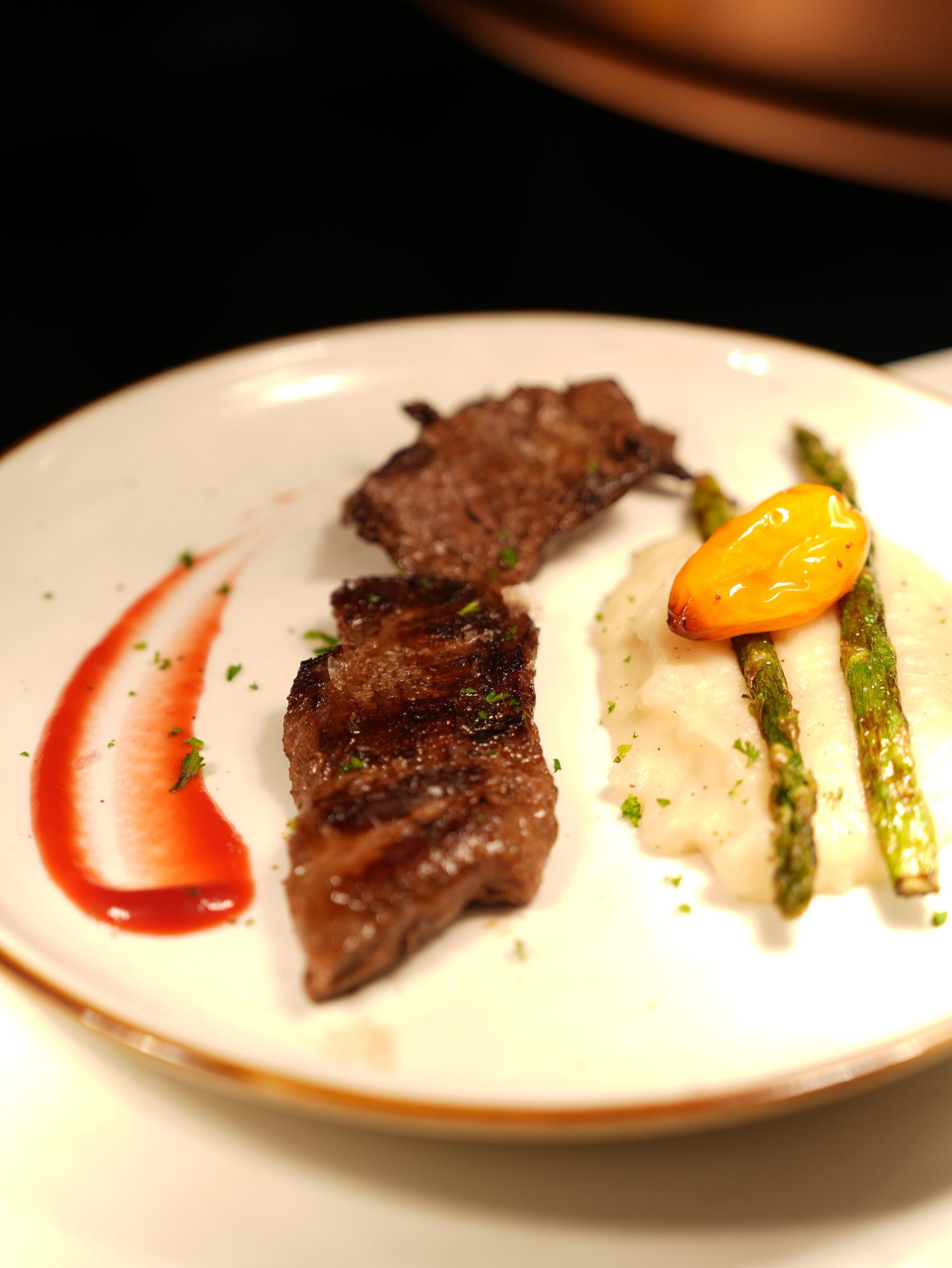 Grilled steak plated with mashed potato, asparagus and roasted pepper